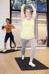 Women of different ages doing stretch exercises for legs with resistance bands while standing on mats