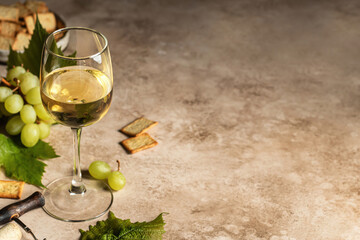 A glass of white wine on textured background with corkscrew and grapes and crackers. Text space