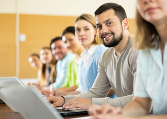 Portrait of a student guy studying on a laptop during a class in a university auditorium