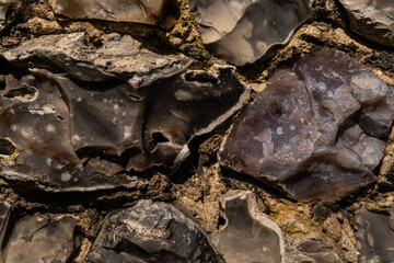 Closeup on various flint stones used in UK as a building material in architecture. Flint is the hardest of building stones, used by the Romans for castle walls and by medieval masons for churches