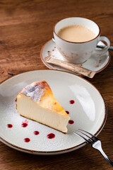 Cheesecake slice, New York style classical cheese cake on wooden background. Slice of tasty cake on white plate served