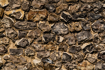 Closeup on various flint stones used in UK as a building material in architecture. Flint is the hardest of building stones, used by the Romans for castle walls and by medieval masons for churches
