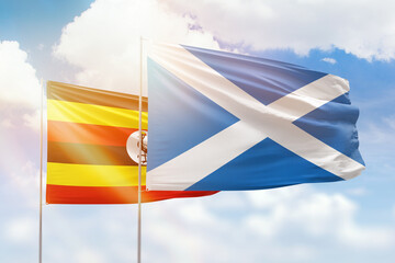 Sunny blue sky and flags of scotland and uganda