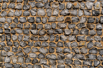 View of a big wall made of flint stones, building material in architecture used in UK. Flint is the hardest of building stones, used by the Romans for castle walls and by medieval masons for churches