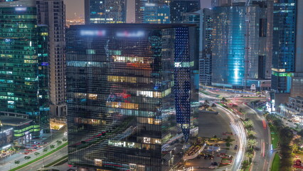 Fototapeta na wymiar Business Bay Dubai skyscrapers with traffic on road intersection aerial night timelapse.