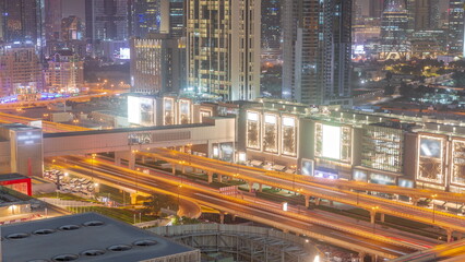 Fototapeta na wymiar Highway road traffic on overpass under footbridge near shopping mall in Dubai downtown night timelapse