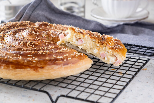 Homemade burek rolled pie with cheese, ham and sesame. Selective focus.