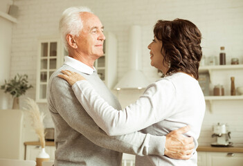 The happy elderly woman and a man dancing in the kitchen