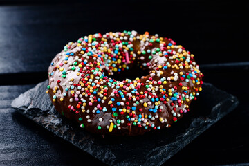dark chocolate glazed donut with mixed colorful sprinkle
