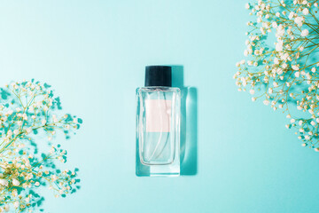 Perfume bottle on light blue background with gypsophila flowers. Beauty, fashion concept. Top view,...