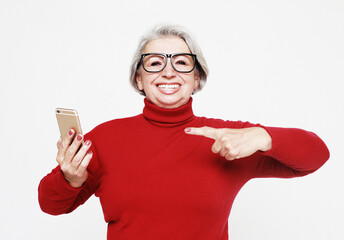 A picture of mature woman wearing red sweater with new smartphone.