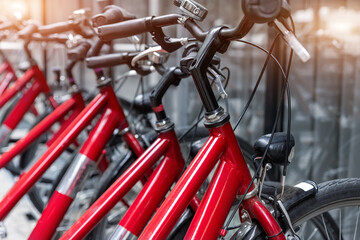 Fototapeta na wymiar Closeup view many red city bikes parked in row at european city street rental parking sharing station or sale. Healthy ecology urban transportation. Sport environmental transport infrastructure
