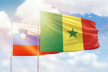 Sunny blue sky and flags of senegal and slovenia