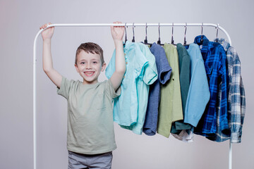 Boy preschooler standing by the hangers, racks up clothes, and chooses clothes for today