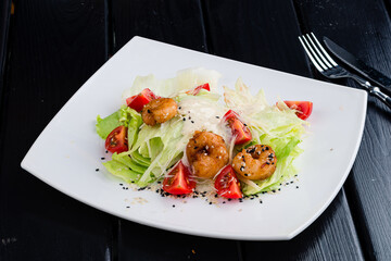 Fresh caesar salad on white bowl with parmesan cheese and shrimps