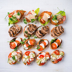 Brushetta set for wine. Variety of small sandwiches with prosciutto, tomatoes, cheese, herbs