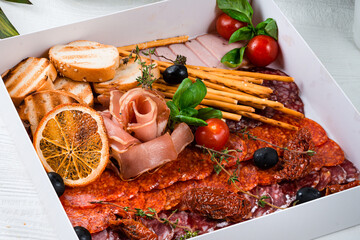 catering box with salami, prosciutto, bacon and breadsticks