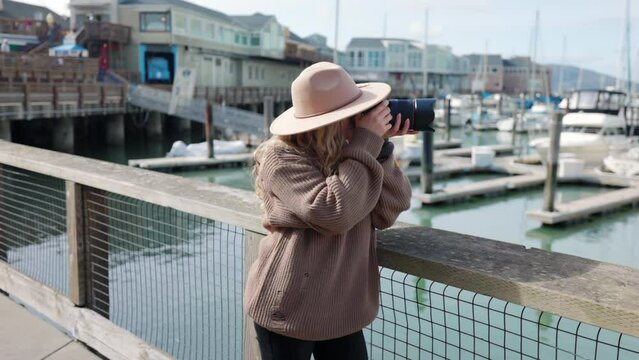 Woman traveling with a camera around coastal town. Female photographer standing at beautiful bay with numerous yachts and boats. High quality 4k footage