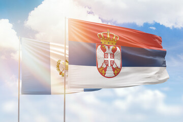 Sunny blue sky and flags of serbia and guatemala