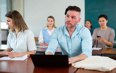 Handsome adult male student typing on laptop during lecture at university