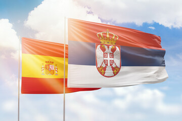 Obraz premium Sunny blue sky and flags of serbia and spain