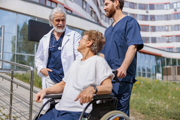 Fototapeta na wymiar Nurse and doctor talking to patient on wheelchair in hospital yard . Rehabilitation concept.