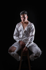 Modelo sentado en una butaca con un atuendo de color blanco