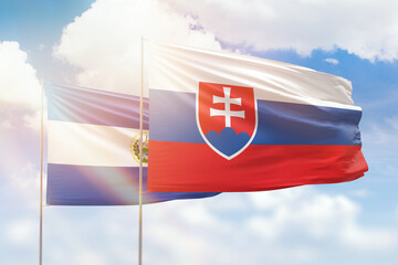 Sunny blue sky and flags of slovakia and el salvador