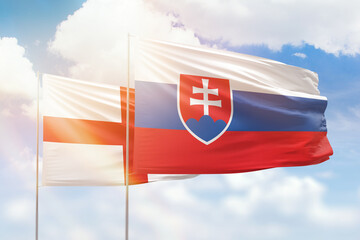 Sunny blue sky and flags of slovakia and england