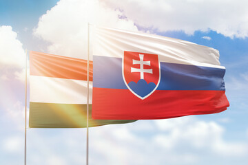 Sunny blue sky and flags of slovakia and hungary