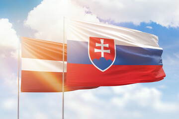 Sunny blue sky and flags of slovakia and latvia