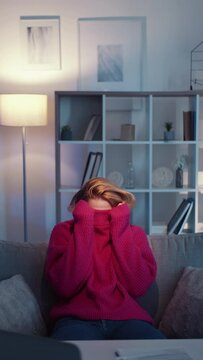 Hiding woman. Silly situation. Meme expression. Unrecognizable lady pulling sweater over head sitting work desk in light room interior looped vertical.