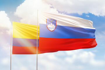 Sunny blue sky and flags of slovenia and colombia