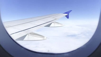Man hand opens aircraft window shade from which airplane wing and clouds can be seen - Powered by Adobe