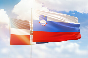 Sunny blue sky and flags of slovenia and dominican republic