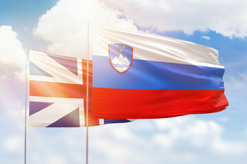 Sunny blue sky and flags of slovenia and great britain