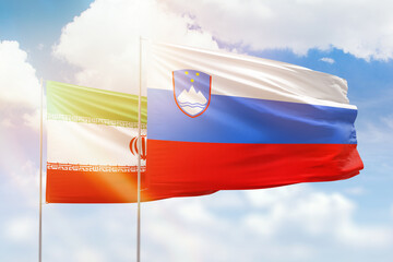 Sunny blue sky and flags of slovenia and iran