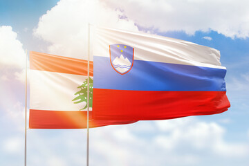 Sunny blue sky and flags of slovenia and lebanon