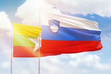 Sunny blue sky and flags of slovenia and myanmar
