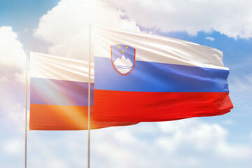 Sunny blue sky and flags of slovenia and russia