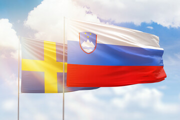 Sunny blue sky and flags of slovenia and sweden