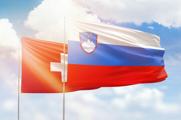 Sunny blue sky and flags of slovenia and switzerland