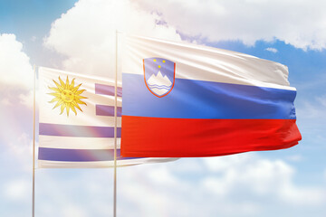 Sunny blue sky and flags of slovenia and uruguay