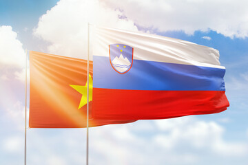 Sunny blue sky and flags of slovenia and vietnam