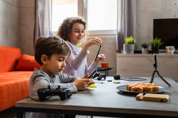 Boy and girl two siblings brother sister making video blogging on mobile phone for online internet blog from their home about favorite toy review create and share content for social network copy space