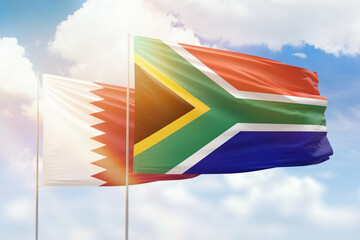 Sunny blue sky and flags of south africa and qatar