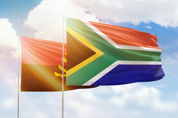 Sunny blue sky and flags of south africa and angola
