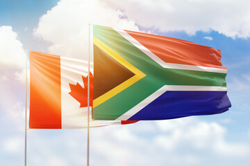 Sunny blue sky and flags of south africa and canada