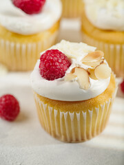 Close-up. Cream muffins topped with fresh raspberries and almonds. Isolated on white background. Recipe book, restaurant and home cooking. Advertising, banner, birthday invitation.
