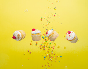 Berry muffins with cream and raspberries on a bright yellow background with colorful confetti....